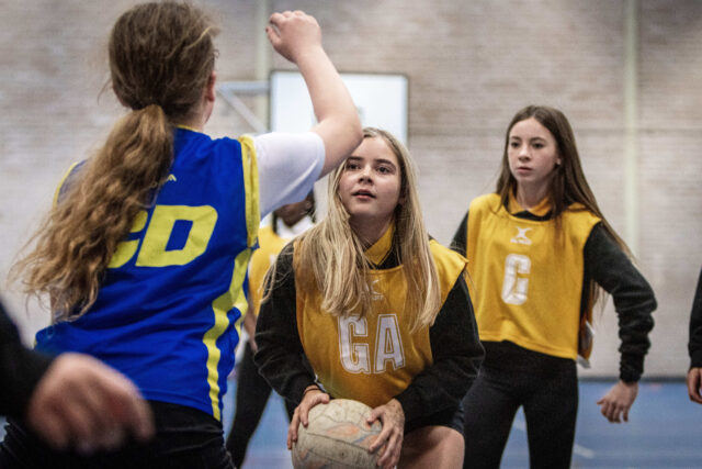 Girls playing netball in the school games hall
